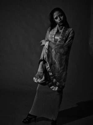 A stylish woman posing in a fashion studio shoot, showcasing traditional attire with a modern twist.