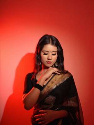 Beautiful portrait of an Indian woman in a traditional black saree with red lighting, showcasing cultural fashion.