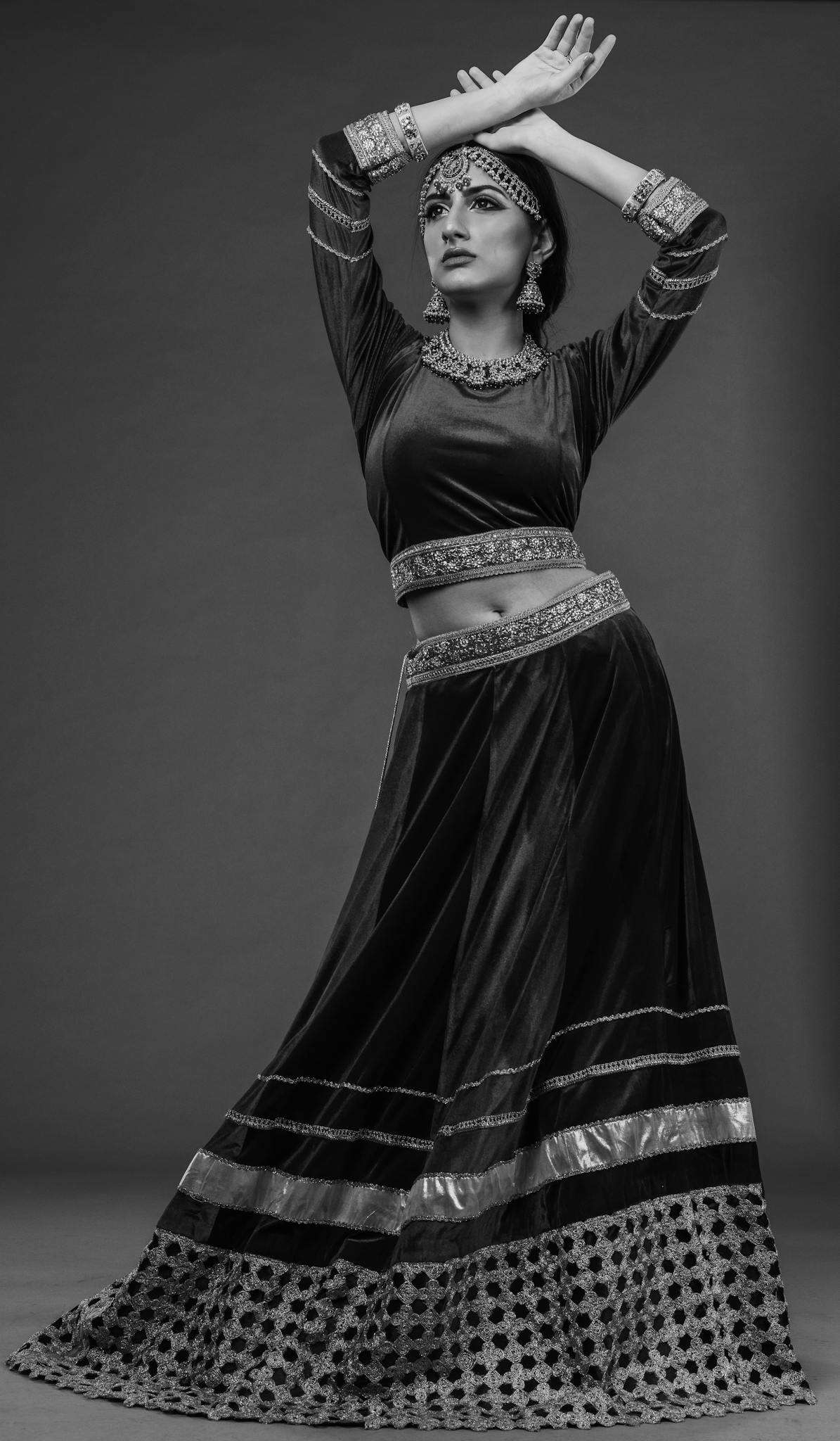 Black and white photo of a woman in a traditional Indian dance pose, studio setting.