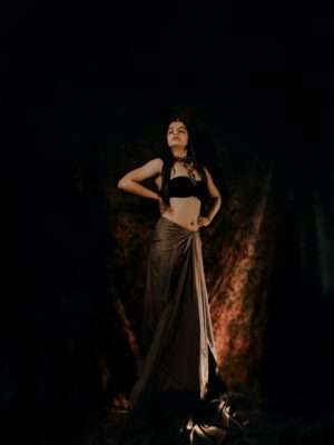 Full-length portrait of a woman in traditional attire. Studio shoot with a dark backdrop.