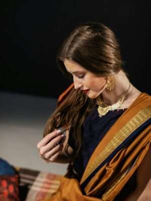 Portrait of a woman in a traditional saree, gazing downward with elegance in a studio setting.