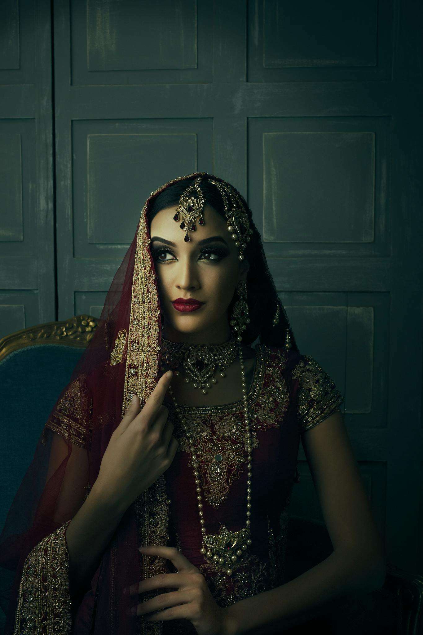 Stunning portrait of a woman wearing intricate traditional jewelry and maroon sari, exuding elegance and grace.
