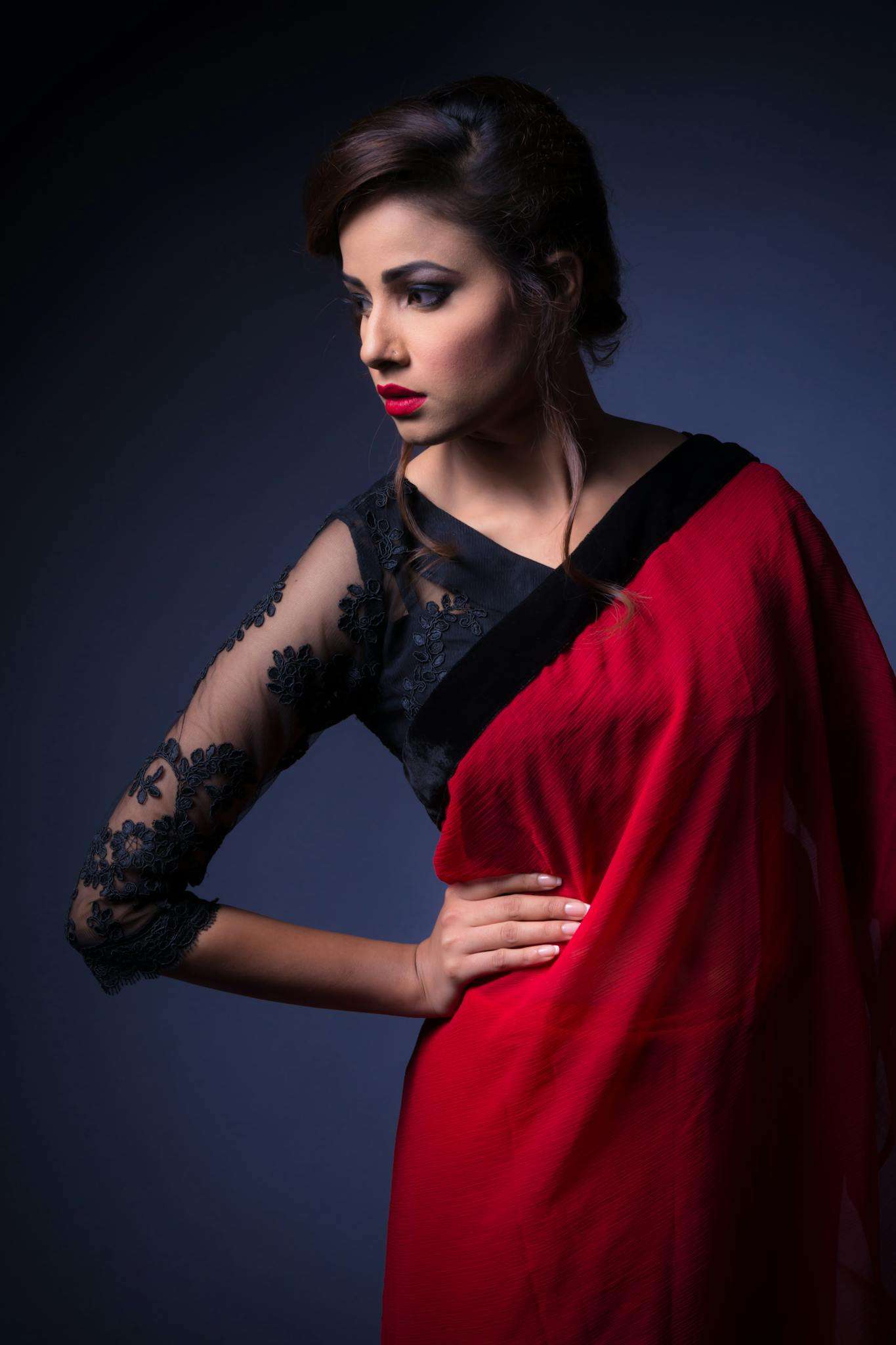 Stylish portrait of a woman in a red and black saree with elegant pose and expression.
